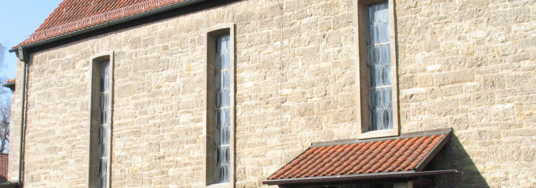 Eine Kirchenwand mit drei Fenstern von außen gesehen