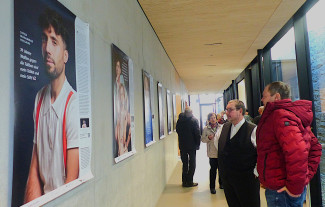 Zwei Männer betrachten im Evangelischen Gemeindehaus in Bad Neustadt das Austellungsplakat mit dem Portraitfoto eines jungen Mannes.